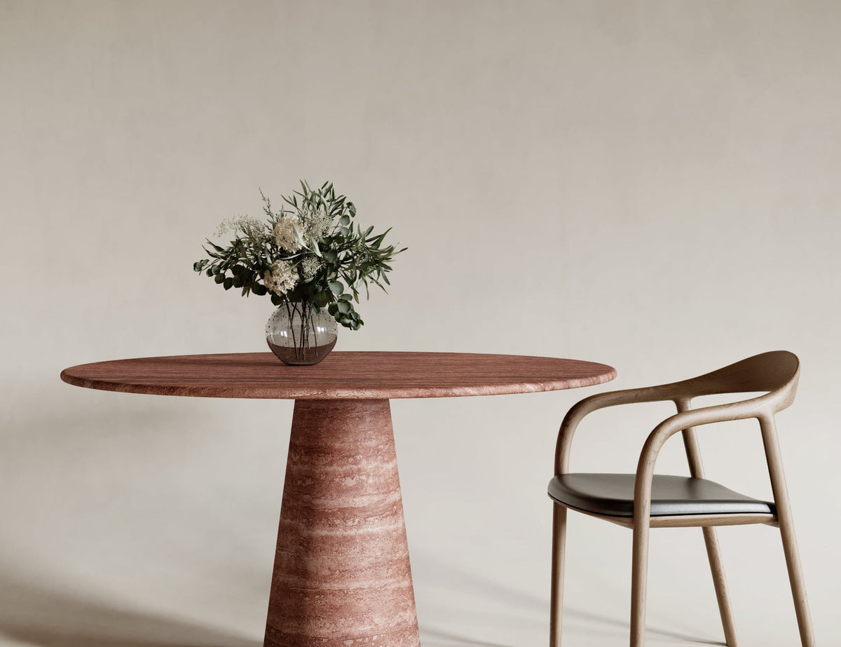 Bold round red travertine dining table with conical leg, warm-toned natural stone finish, striking sculptural centerpiece, modern travertin design, perfect for statement dining