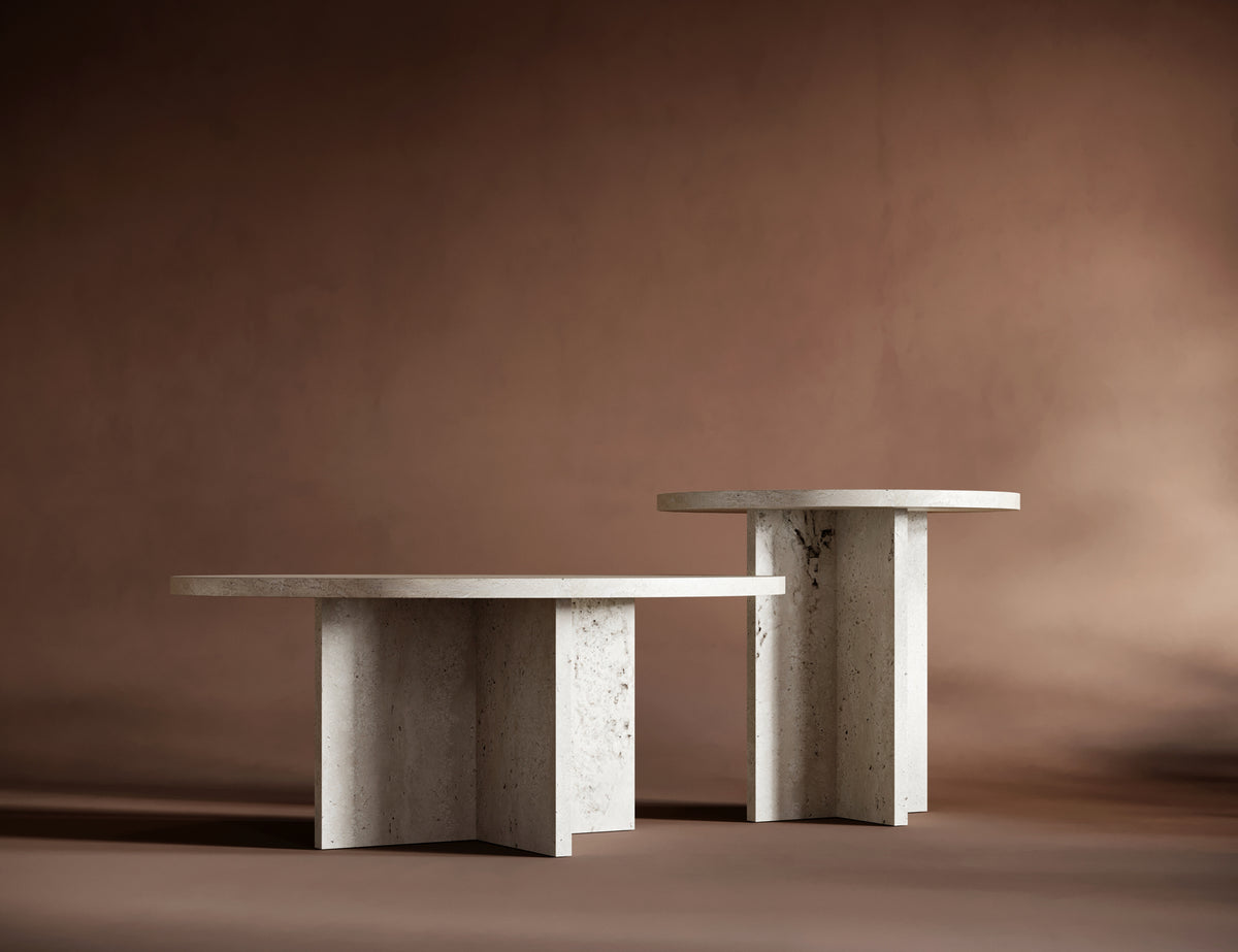 A dynamic arrangement of the ELENA travertine tables, showcasing their contrasting heights and sculptural elegance.