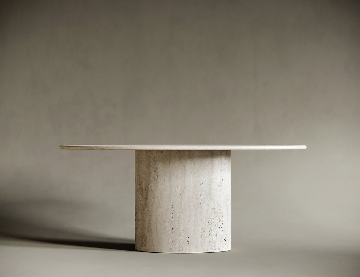 Close-up of a travertine tabletop with a rounded edge, showcasing its natural stone texture and subtle veining. The light beige surface features a honed finish, emphasizing the organic beauty of the material. Set against a neutral gray background, this detailed shot highlights craftsmanship and modern design.