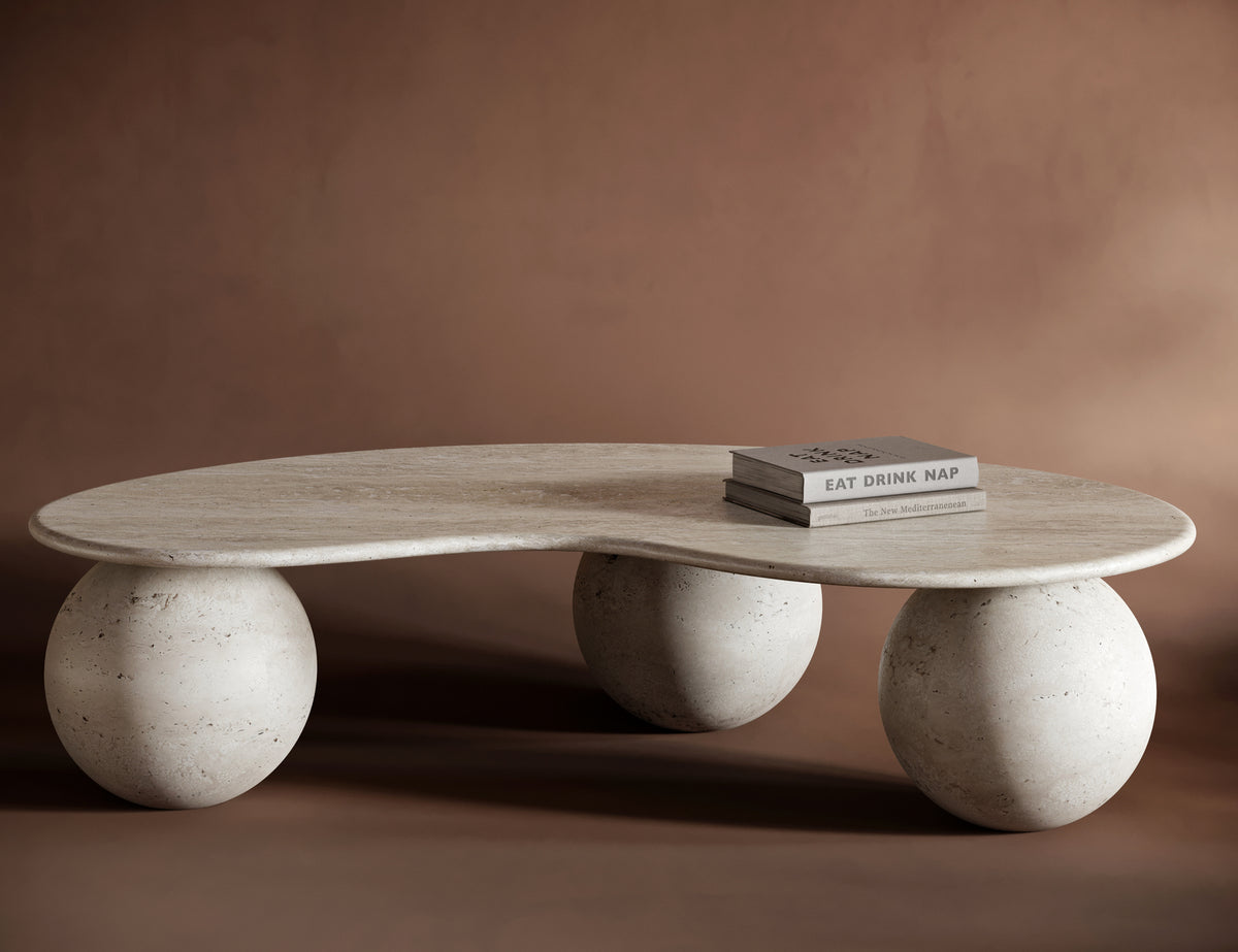 FABIO travertine coffee table with a free-form, flowing top and sculptural spherical bases, showcasing natural stone textures.