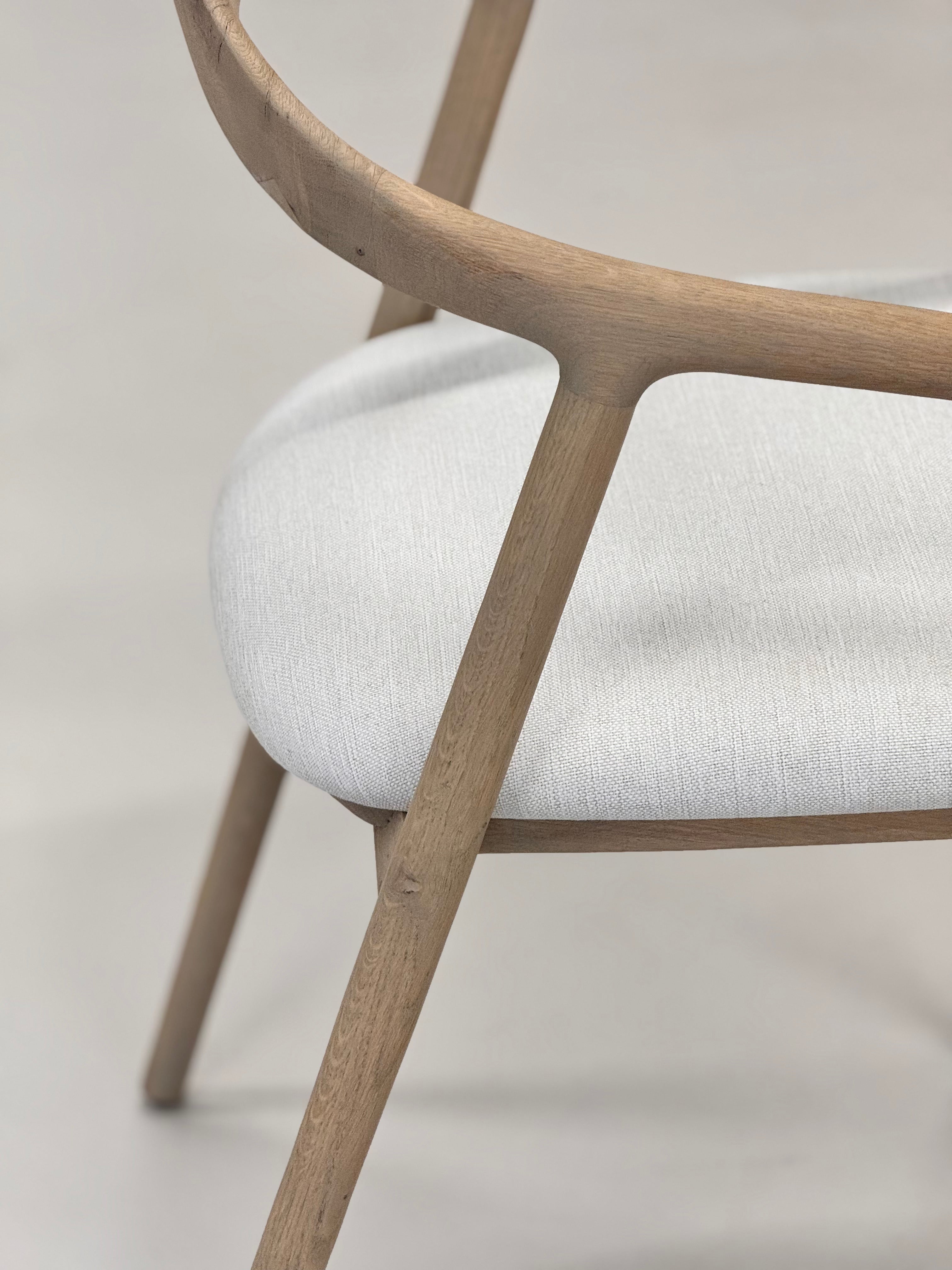 Chair with wooden frame and white cushion on a light background