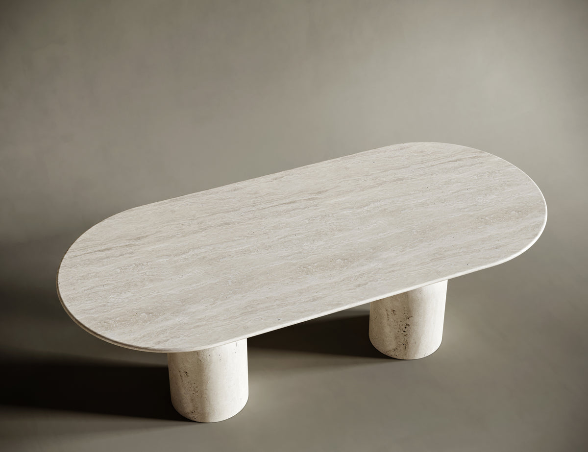 Detailed view of the hourglass-shaped travertine legs of an oval dining table, showcasing their sculptural elegance and solid craftsmanship. The natural stone texture adds depth and character to this luxurious design.