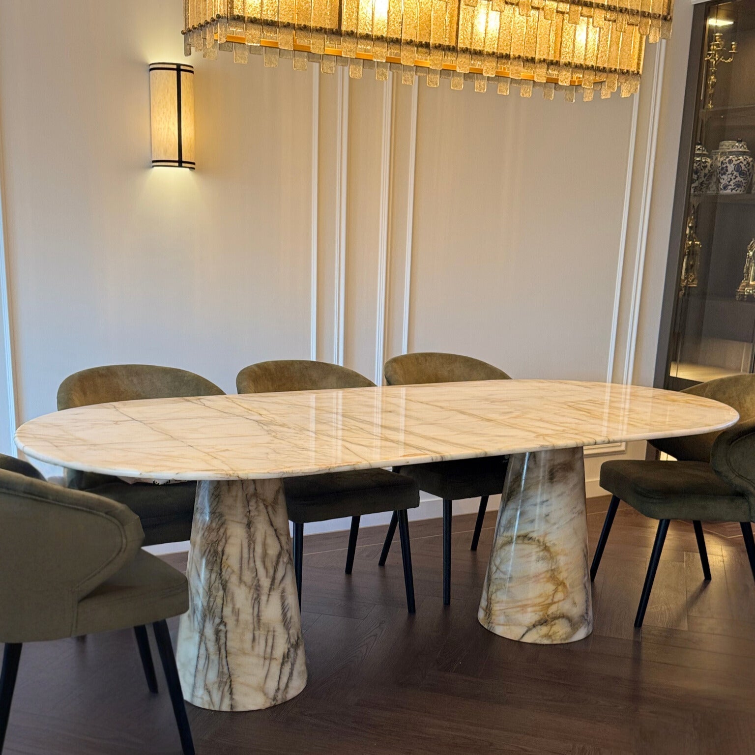 Dining room with a marble table and chairs under a chandelier.