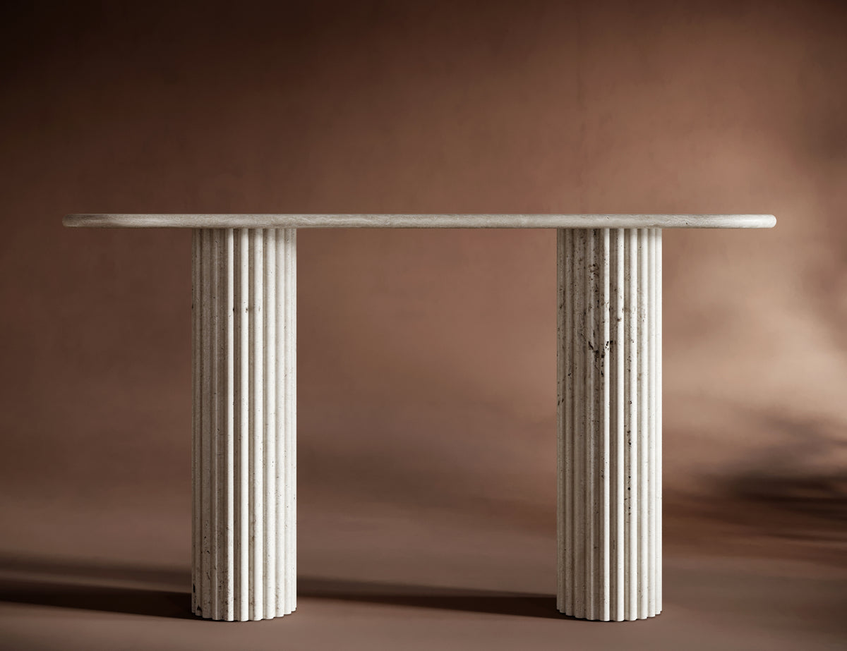 Elegant travertine console table set against a warm brown background, emphasizing its timeless and sculptural design.