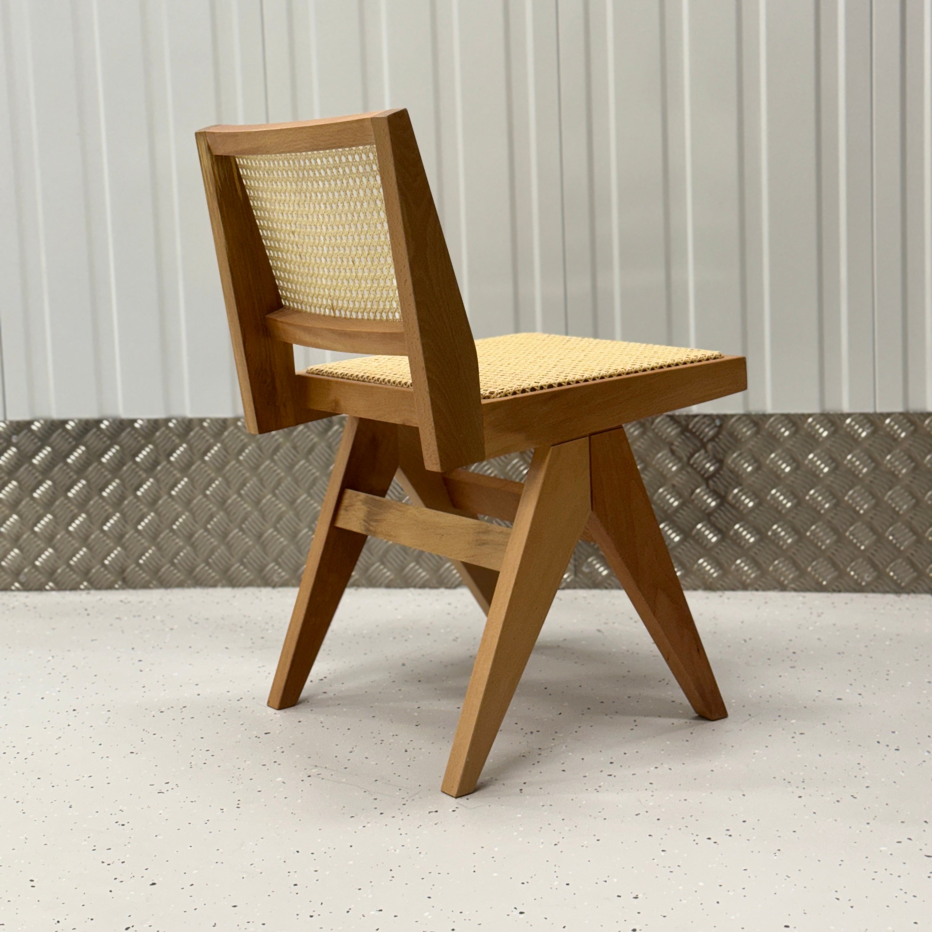 Handcrafted dining chair with a minimalist wooden structure and natural rattan seat, offering a blend of style and comfort for modern interiors.