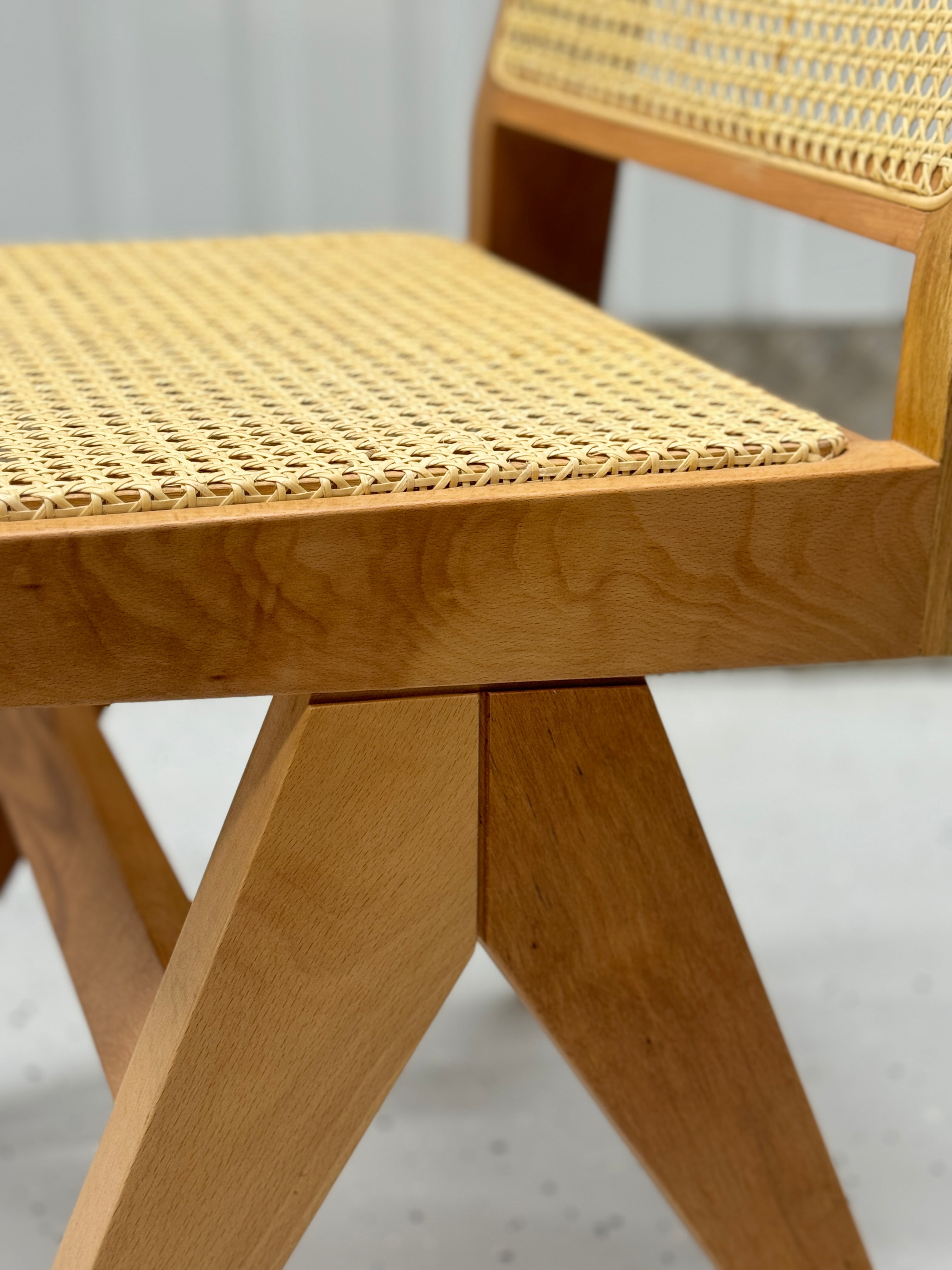 Pierre Jeanneret-inspired chair with a refined wooden frame and airy rattan details, ideal for creating a sophisticated yet relaxed dining atmosphere.