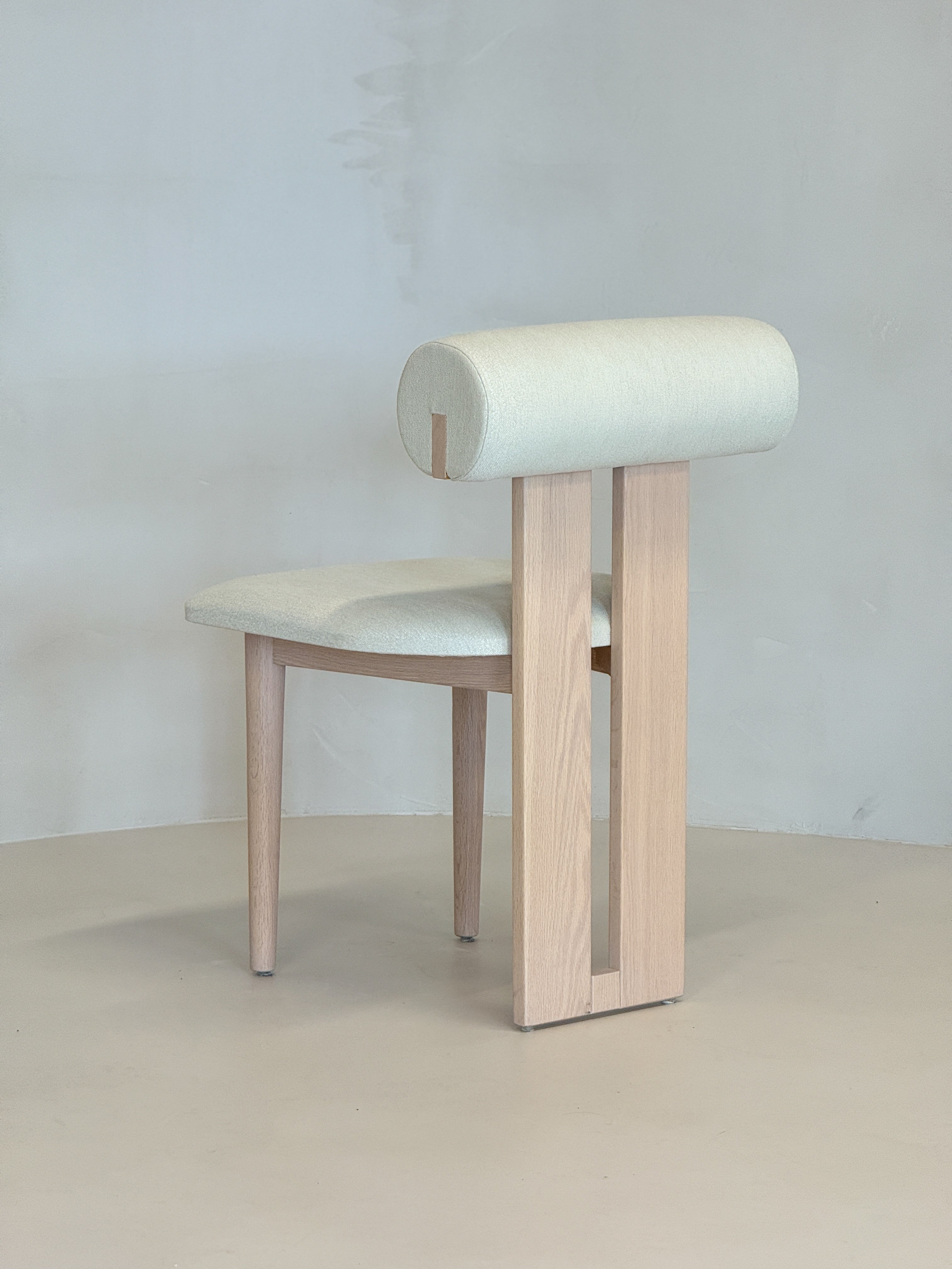 "Minimalist Roll Chair with a cushioned cylindrical backrest, blending natural wood and refined design by BEDÚ Atelier."