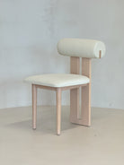 wooden "Roll Chair by BEDÚ Atelier featuring a cylindrical backrest and solid wood frame, perfect for modern dining spaces."