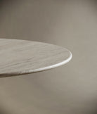 Close-up of the round travertine tabletop, emphasizing its seamless edge and intricate stone veining. The honed finish highlights the table's natural elegance and timeless appeal.