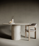 Sculptural round travertine dining table with a unique rounded base, blending soft organic geometry with solid stone elegance; a contemporary interpretation of classic materiality for modern interiors.