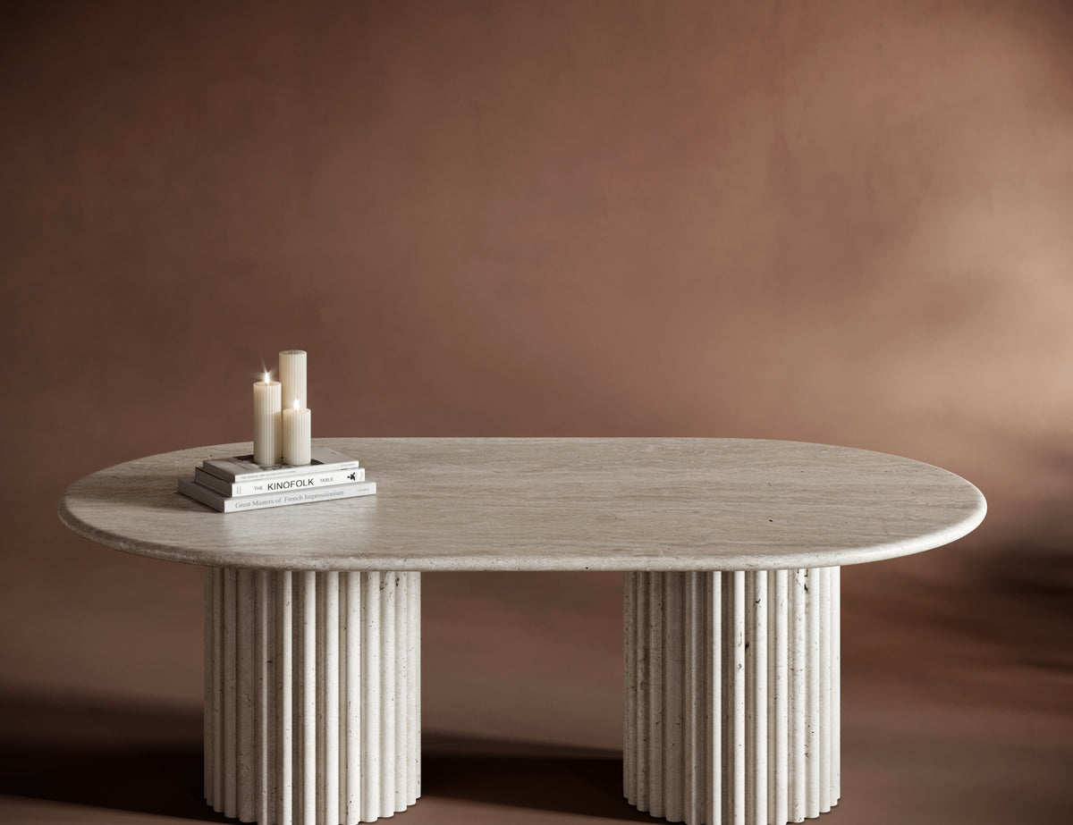 SERENA travertine coffee table with an oval top and fluted cylindrical bases, showcasing natural stone textures.