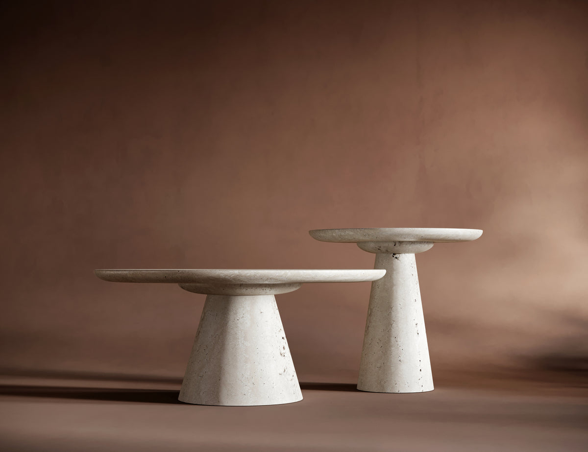 SOFIA travertine coffee table set arranged dynamically against a warm brown background, emphasizing its timeless design.