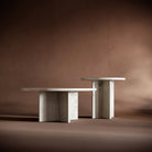 A dynamic arrangement of the ELENA travertine tables, showcasing their contrasting heights and sculptural elegance.
