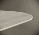 Detailed close-up of a travertine tabletop, highlighting its rounded edge and natural stone texture with subtle veining. The light beige surface features a honed finish, showcasing the craftsmanship and organic beauty of the material. Perfect for modern, minimalist interiors and luxury furniture design