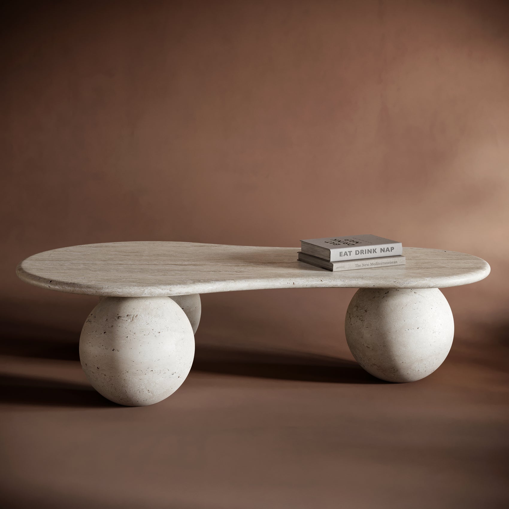 MARCO travertine coffee table with an organic, pebble-shaped top and spherical legs, showcasing natural stone textures.
