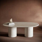 MATTEO travertine coffee table with an oval top and cylindrical bases, showcasing natural stone textures.
