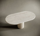 Modern oval travertine table with ribbed base on a neutral background