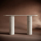 Elegant travertine console table set against a warm brown background, emphasizing its timeless and sculptural design.
