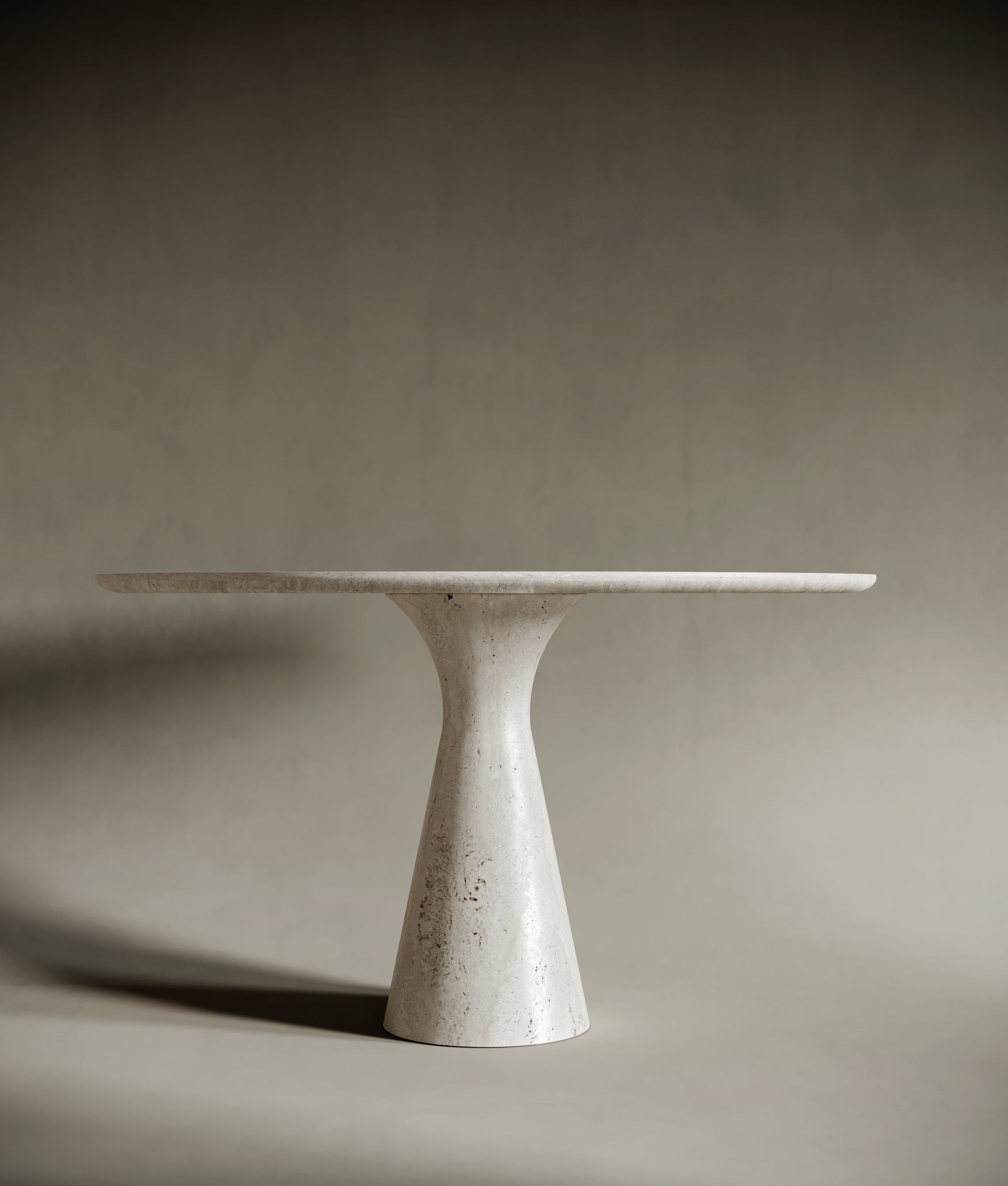 Close-up of a round travertine tabletop, emphasizing its natural stone texture, soft veining, and honed finish. The light beige surface reflects the organic beauty and artisanal quality of the material, perfect for sophisticated interiors