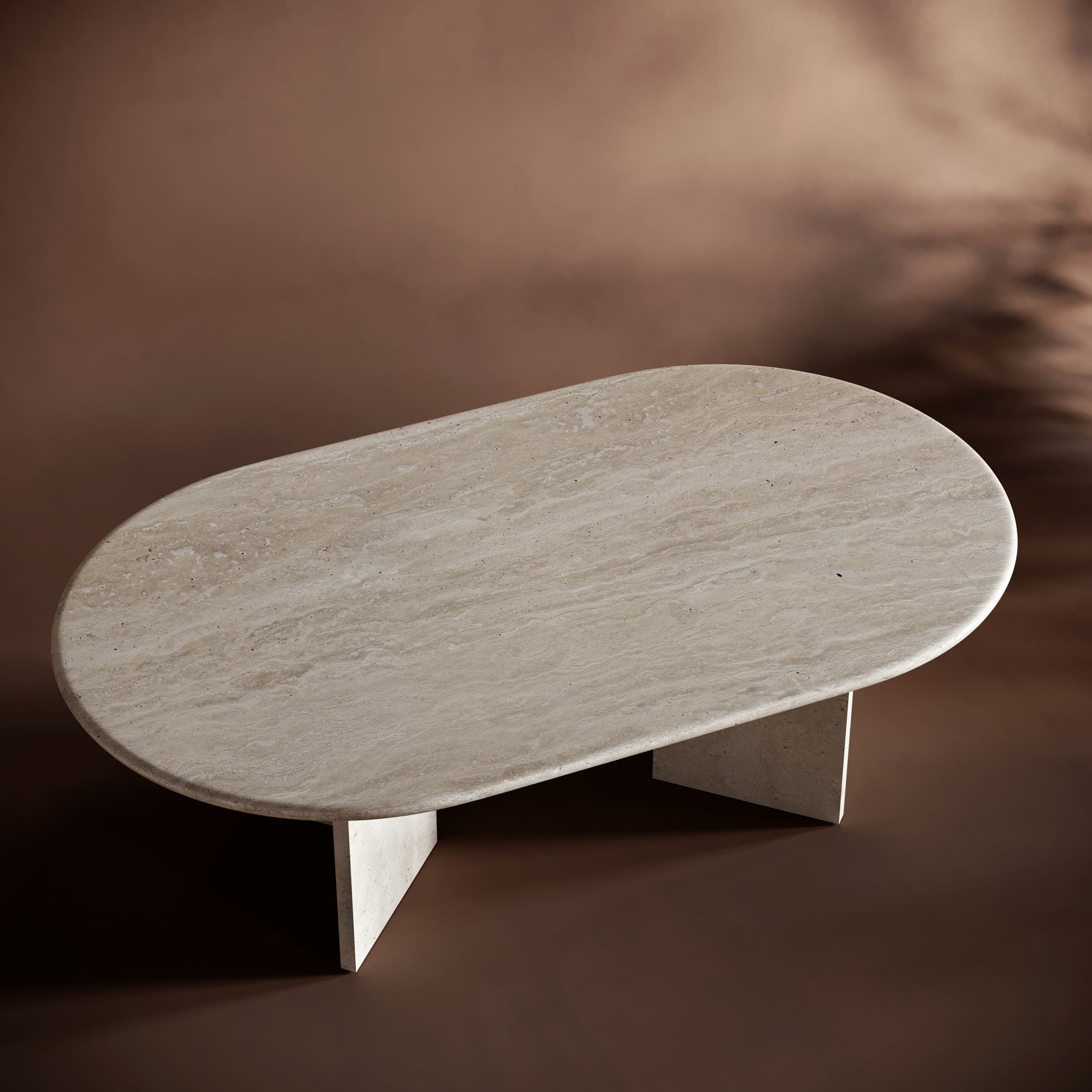 Oval-shaped travertine coffee table on a brown background